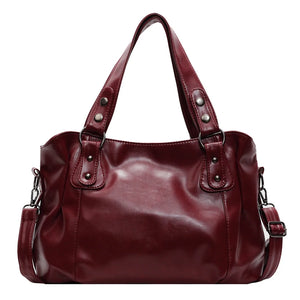 A burgundy red large capacity shoulder bag with a soft vegan leather finish, featuring two handles and a detachable strap.
