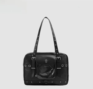 Black handbag with studded details on a light gray background and silver accessories 